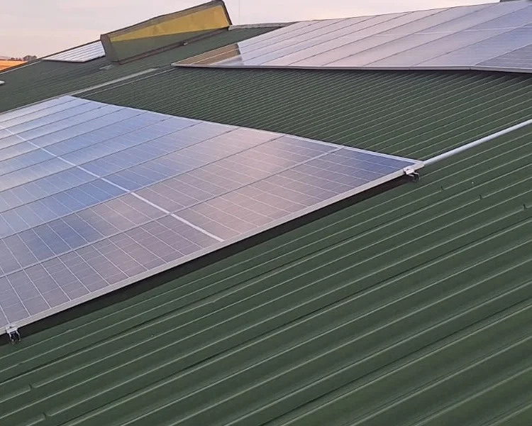 Close view of a roof-mounted solar array on a green corrugated roof